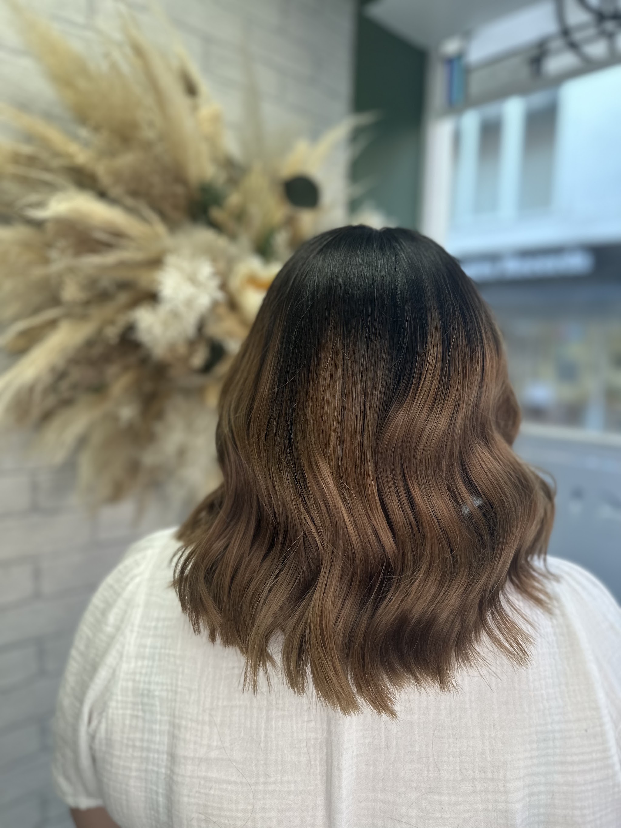 Brunette balayage waves in front of the studio’s pampas display